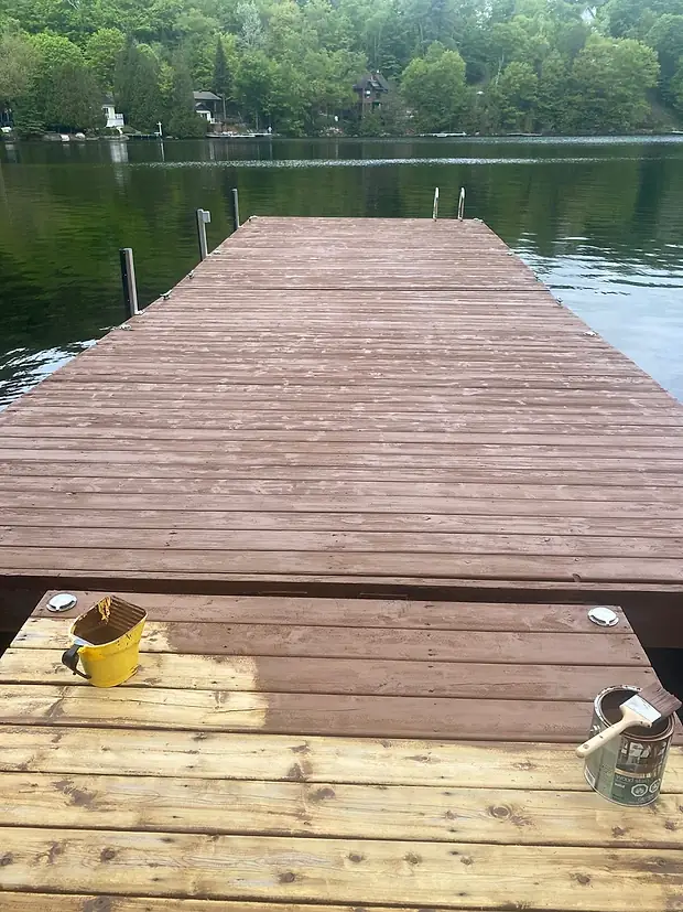 Le quai teint brun foncé jusqu'aux poteaux du bout, la chaudière et le pot de teinture avec son pinceau encore posés sur les planches du bord