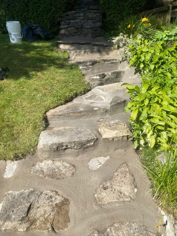 Le même haut de chemin refait : joints frais entre les pierres, marches nettes jusqu'à l'escalier