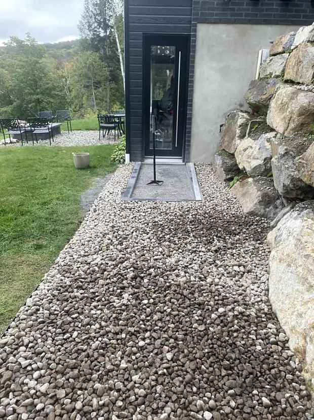 La même allée latérale en pierre concassée, avant la pose des dalles, jusqu'à la porte vitrée