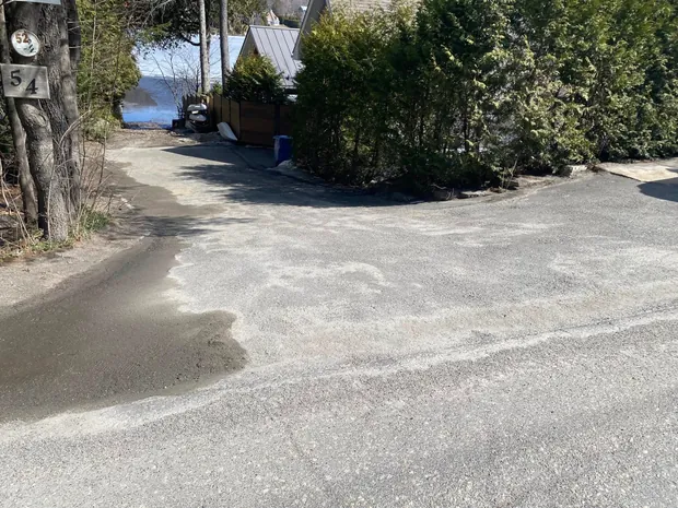 Le bord de la même entrée ratissé au printemps, le sable repoussé sur les côtés, haie de cèdres le long de la rue
