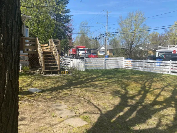 La même clôture peinte en blanc, vue depuis la cour, avec l'escalier de bois de la maison