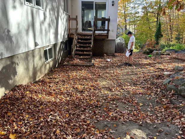 Vieil escalier de bois raide et étroit devant une maison blanche, terrain couvert de feuilles d'automne