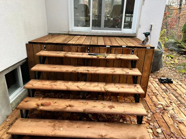 Gros plan du nouvel escalier large, structure d'acier noire et bois couleur cognac