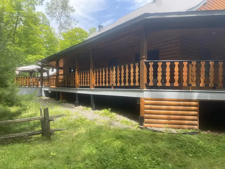 Vue d'ensemble depuis le terrain : la longue galerie teinte sur toute la façade