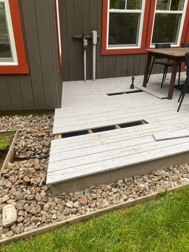 Deux planches de la terrasse retirées pour passer sous le plancher, sous le panneau électrique gris